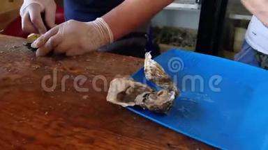 新鲜牡蛎在鱼市<strong>开张</strong>。 售货员手里拿着一只牡蛎和一把用来切东西的刀。 海鲜，典型的沿海食品
